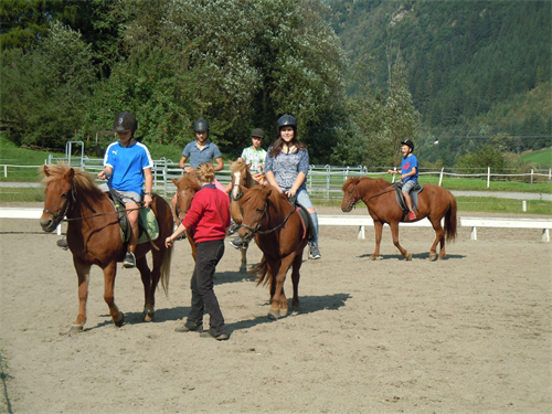 eine Gruppe von Menschen, die auf dem Rücken eines braunen Pferdes reiten